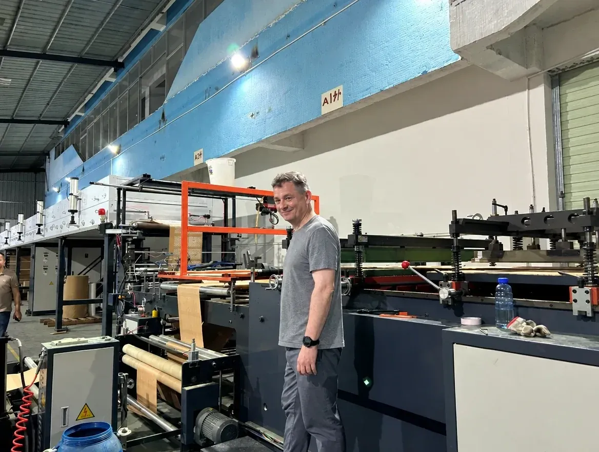 Noel Murphy beside a mailer production line in China