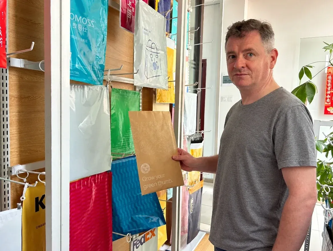 Noel Murphy comparing mailer bag samples at a packaging supplier in China