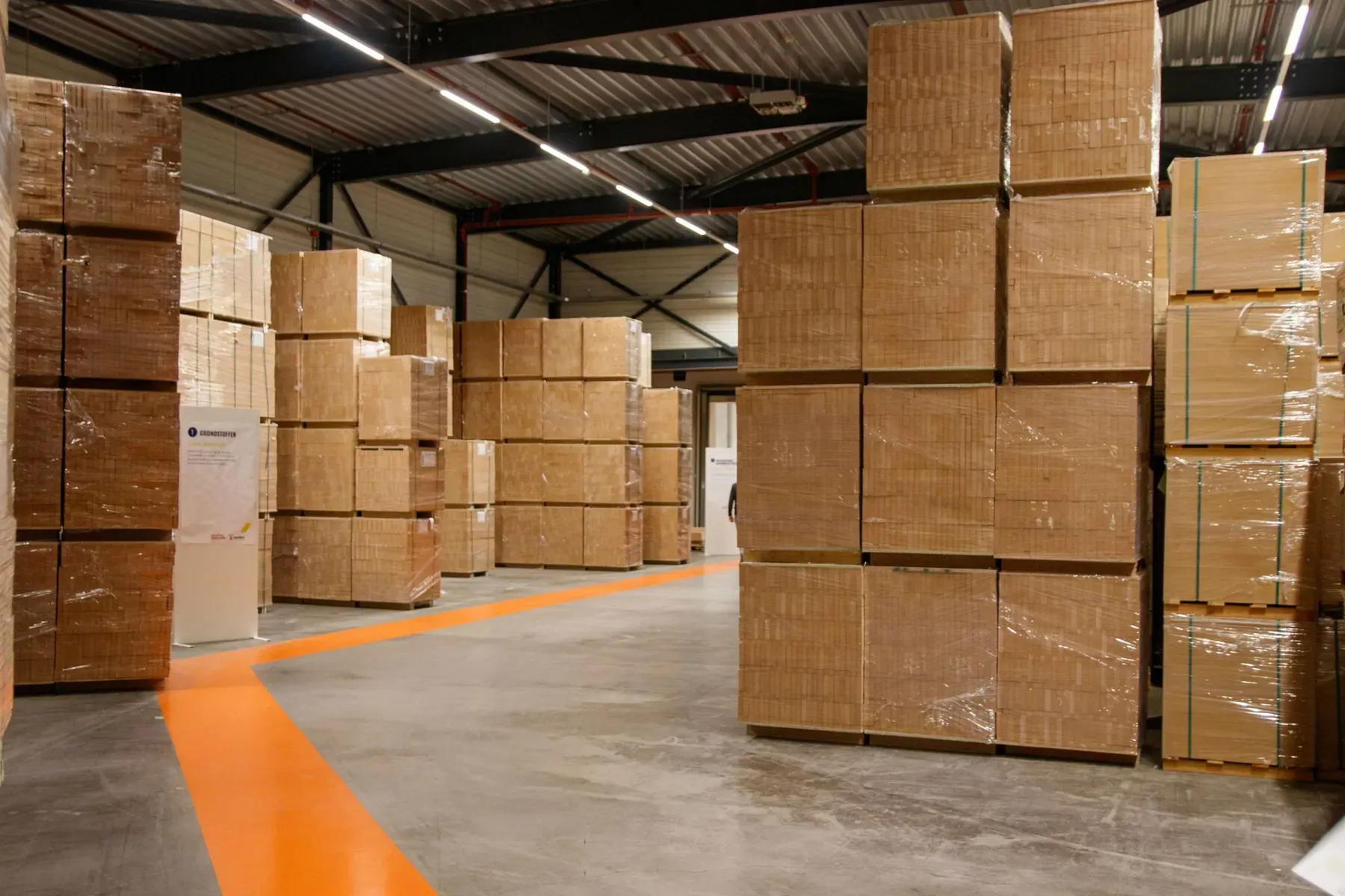 Cartons stacked in rows on the floor of a large warehouse